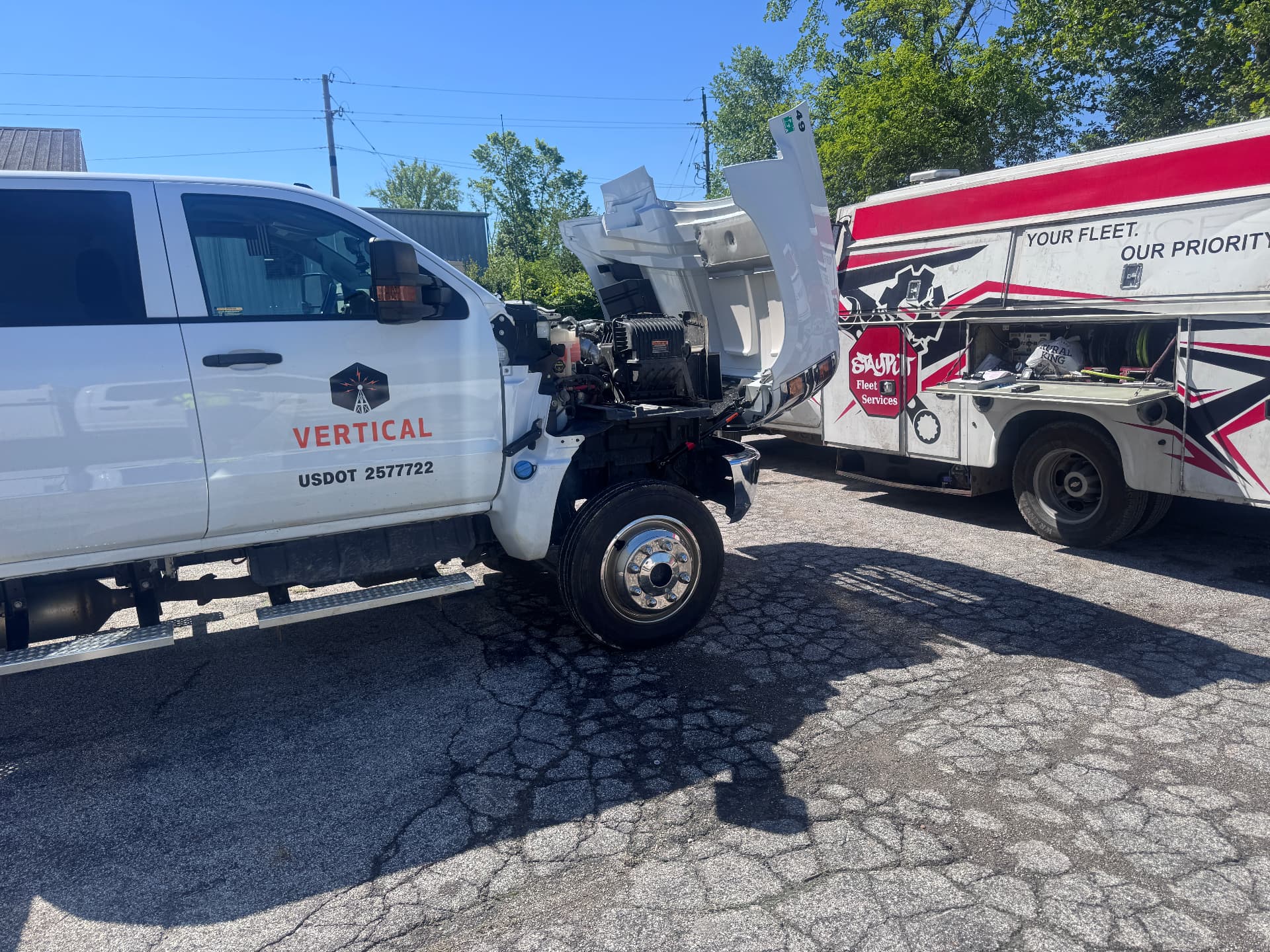 White Vertical service truck with hood tilted forward next to StayPut truck