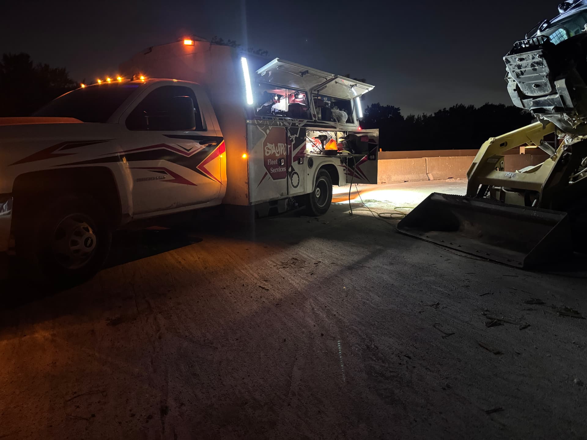 StayPut service truck working under floodlights at night on a highway job site