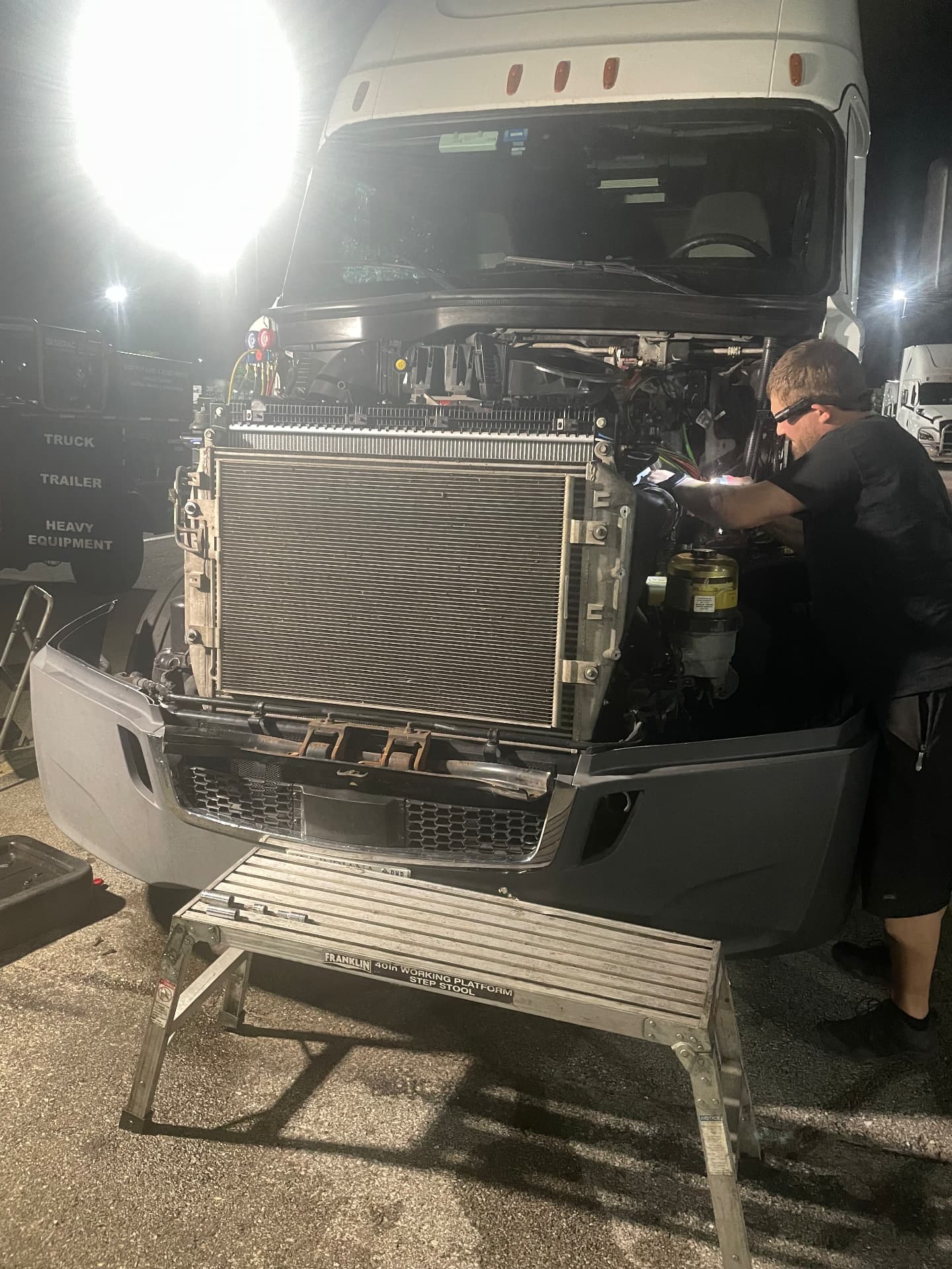 StayPut technician working under lights on a Freightliner cooling system at night
