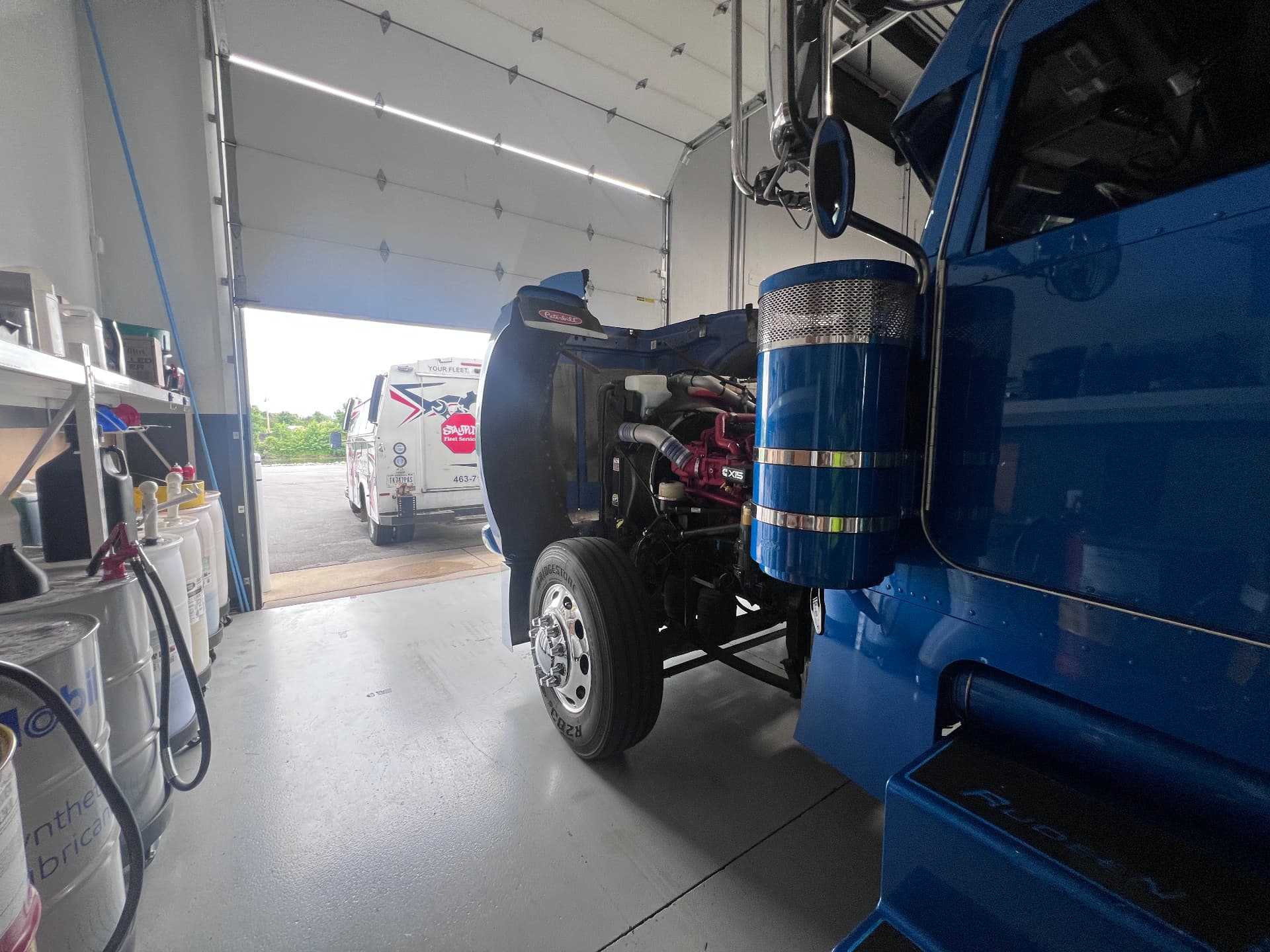 Blue Peterbilt with hood open next to a StayPut service truck at the shop bay