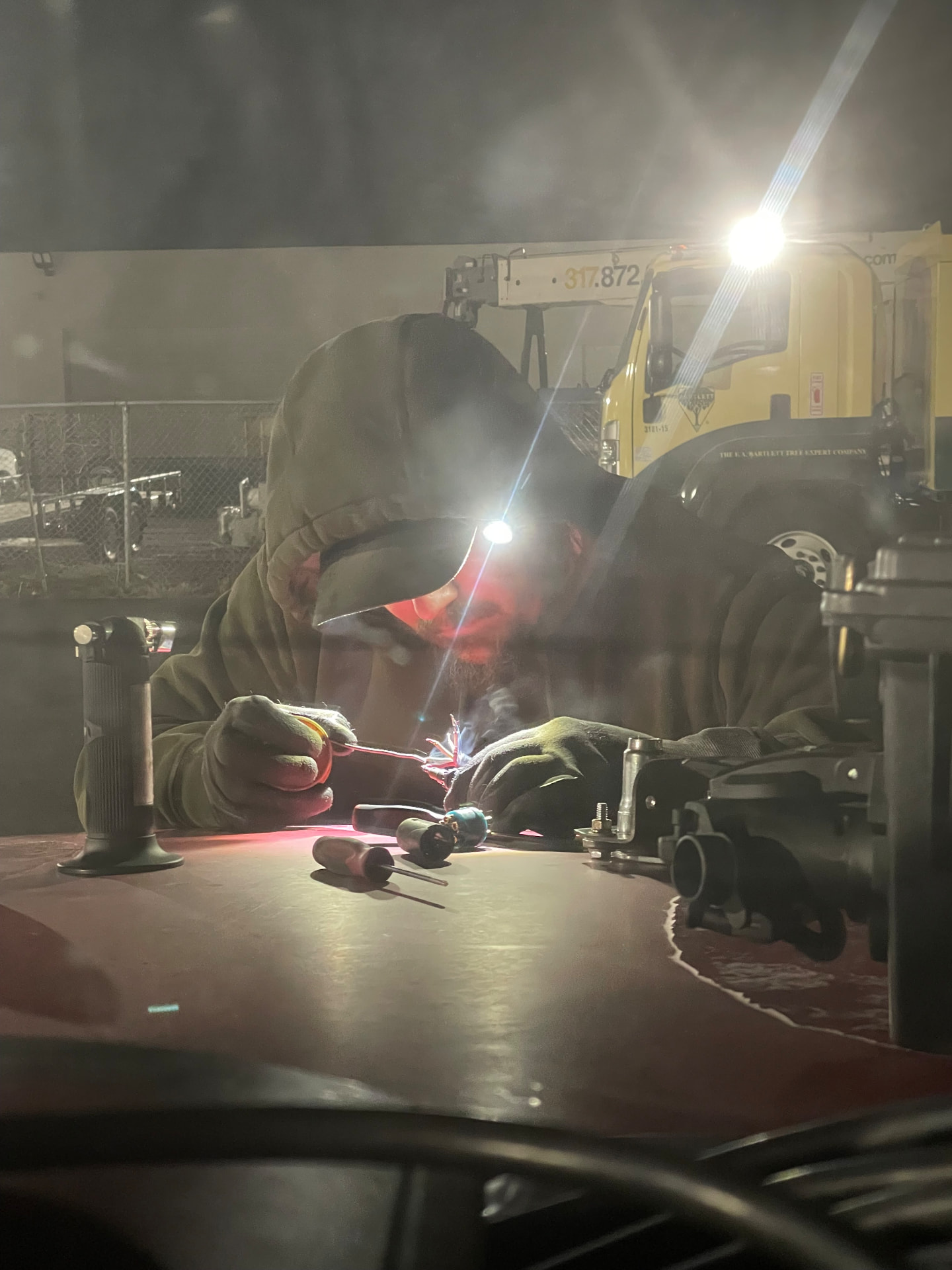 StayPut technician repairing wiring by headlamp at night beside a bucket truck